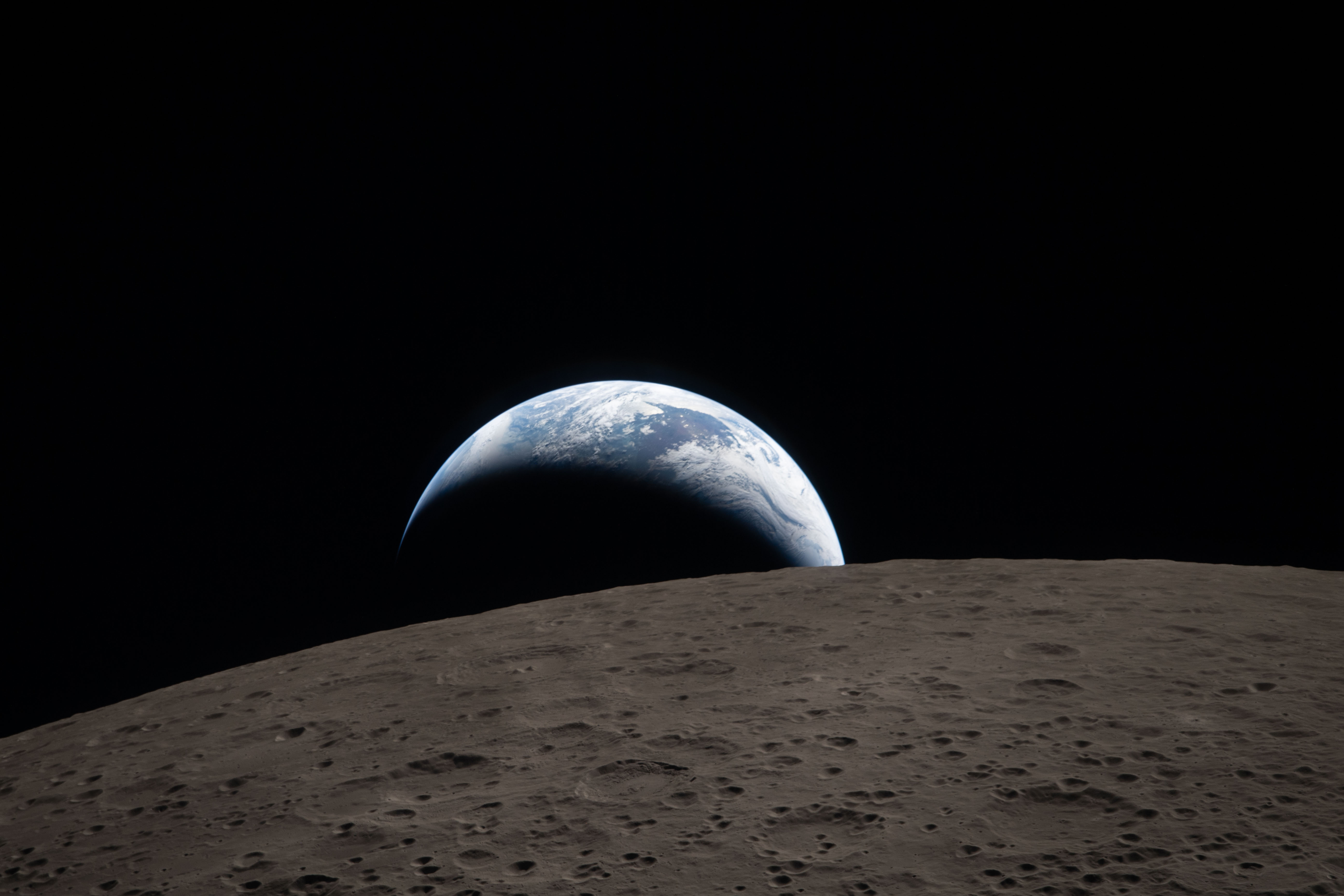Earthset: Earth sets behind the cratered lunar surface as seen from Orion
